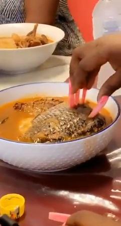 Moment lady struggles to eat fish with long attached nails (Video)