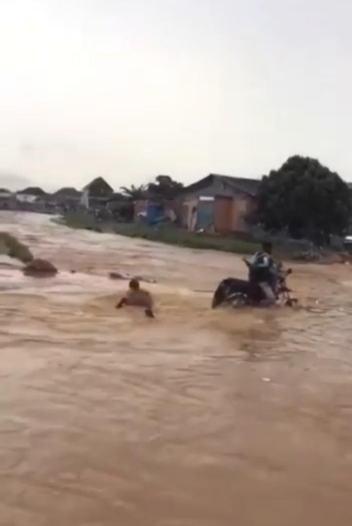 Onlookers stare helplessly as flood washes away man and bike (Video)